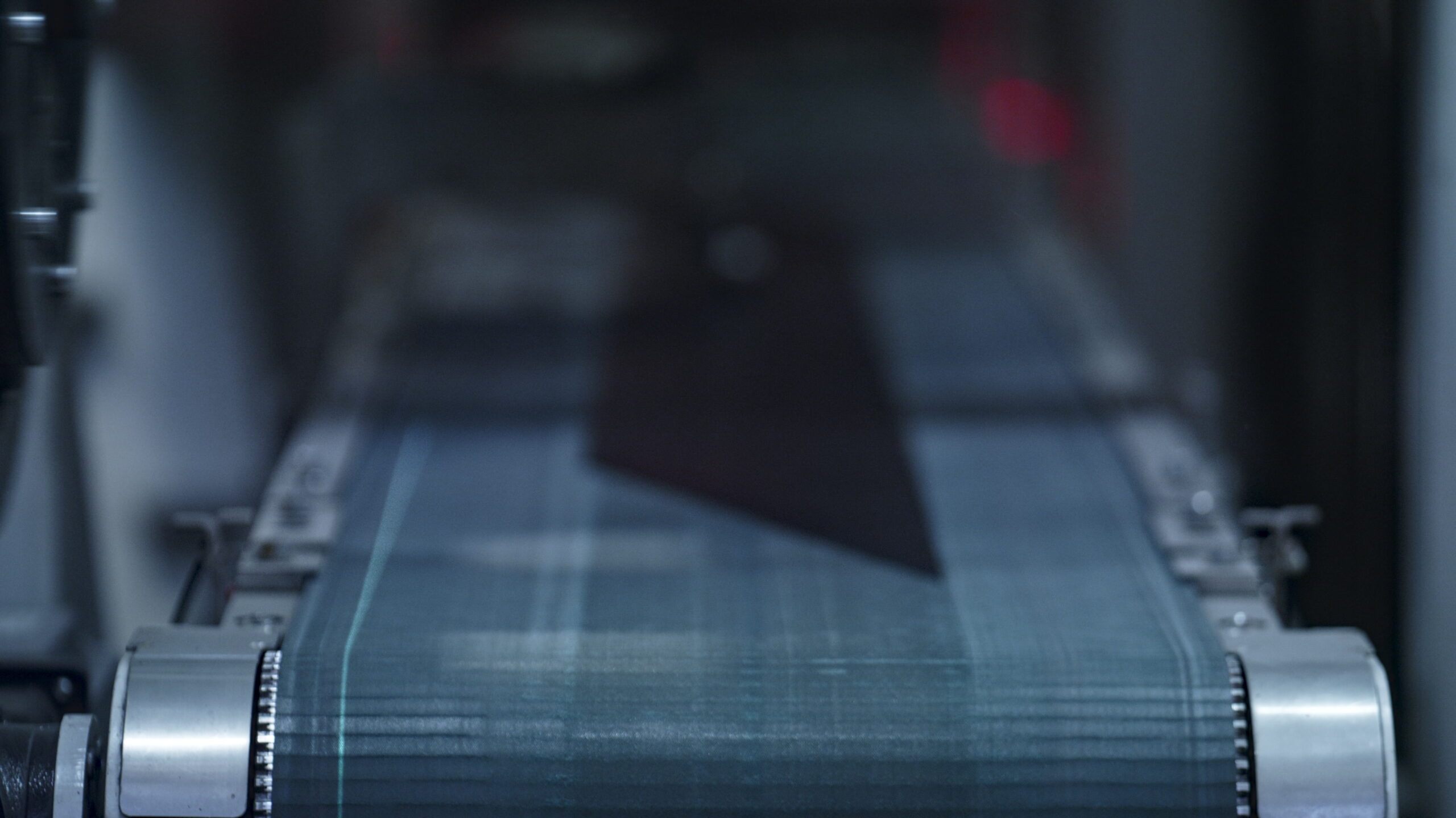 A close-up view of a moving conveyor belt in an industrial setting showcases PolyWiz technology at work, with the center in focus and the surroundings slightly blurred.