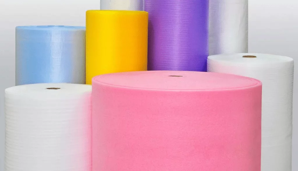 Rolls of packing foam in various colors—pink, yellow, purple, blue, and white—are displayed upright against a plain background. These vibrant rolls offer excellent cushioning and serve as eco-friendly alternatives to traditional styrofoam when paired with Better Densifiers.