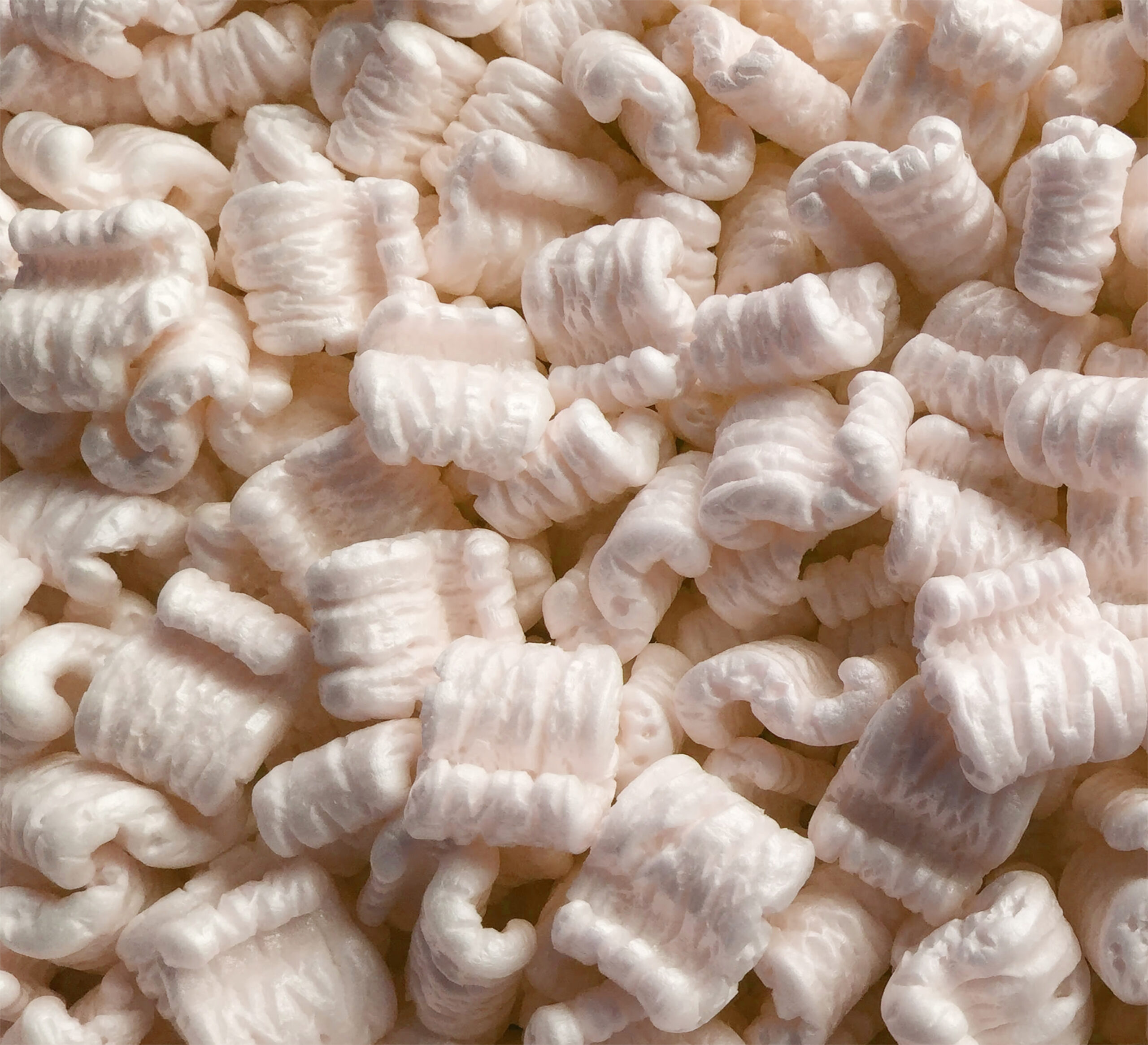 A close-up view of a pile of white packing peanuts, showing their textured, curved surfaces and soft, spongy appearance—these styrofoam pieces are commonly used for cushioning items during shipping and can be processed through styrofoam recycling programs.