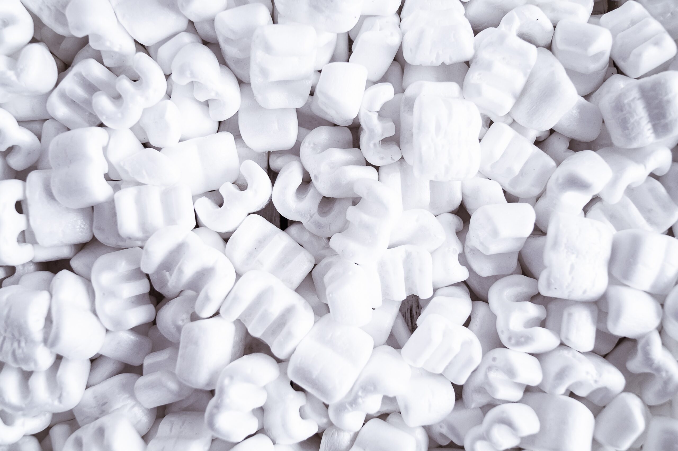 A close-up of many white styrofoam packing peanuts, used as protective packaging material, filling the entire frame.